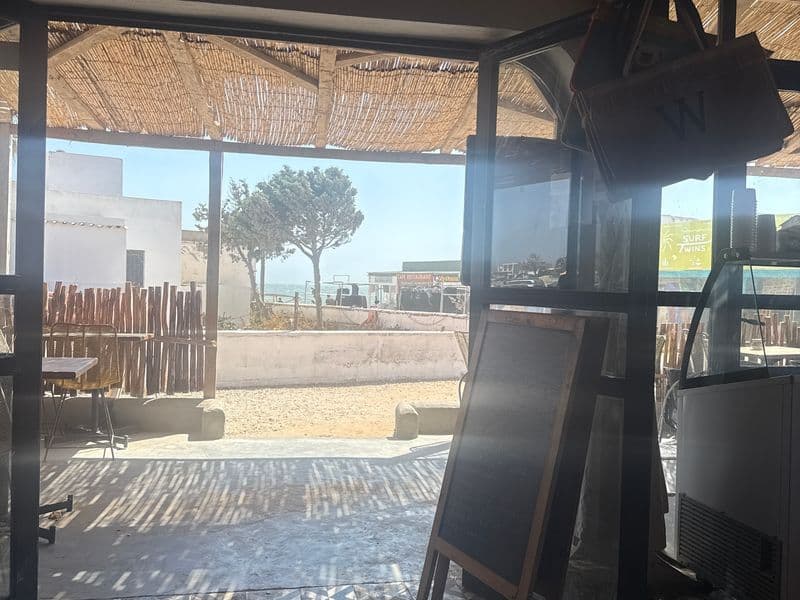 Vue depuis la salle vers la terrasse et la mer à travers l'auvent en roseau